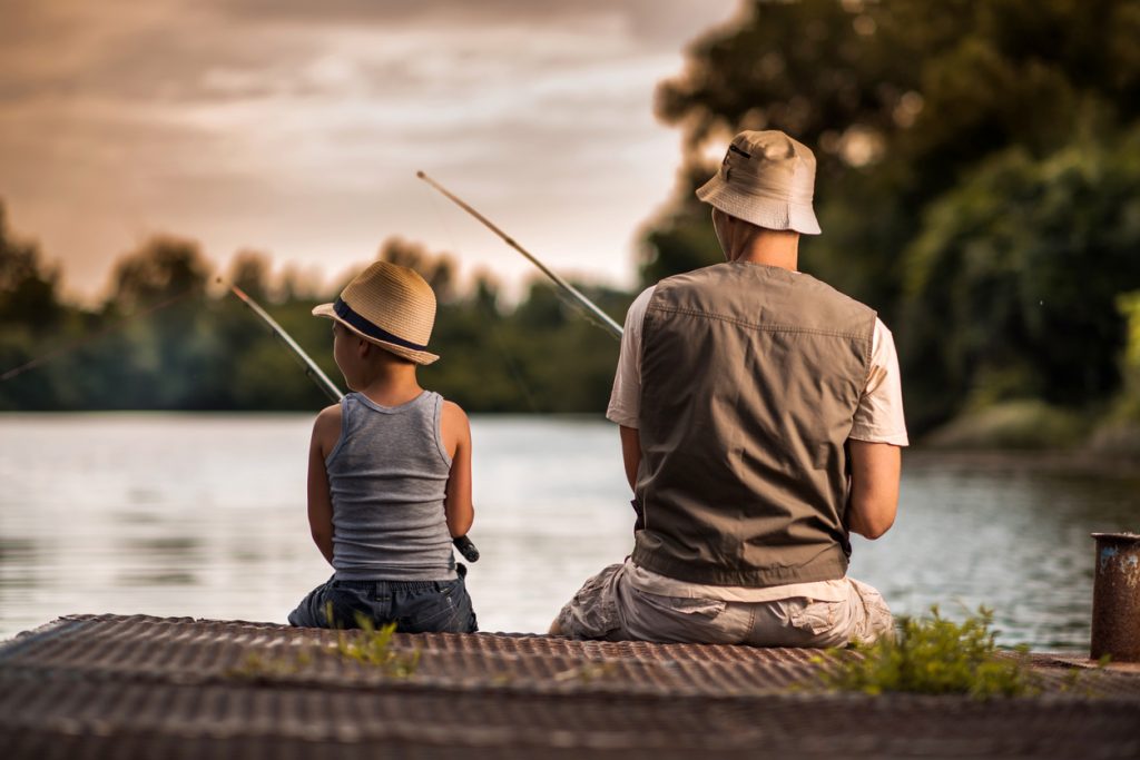 Rear view of a father and son at fishing rodeo