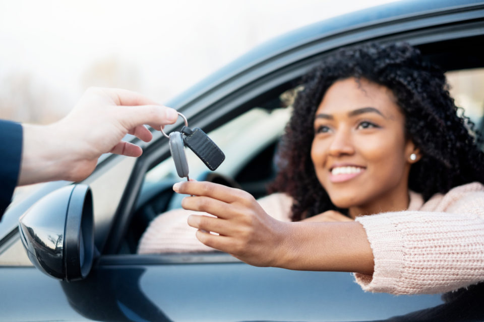 Happy woman receiving keys to her new car.