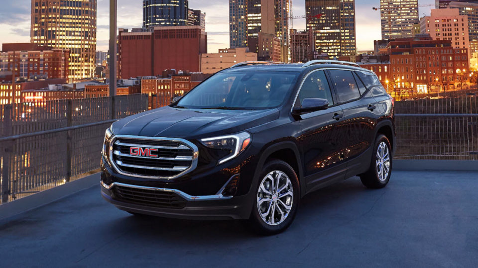 A black GMC Terrain SUV against a cityscape at twilight.