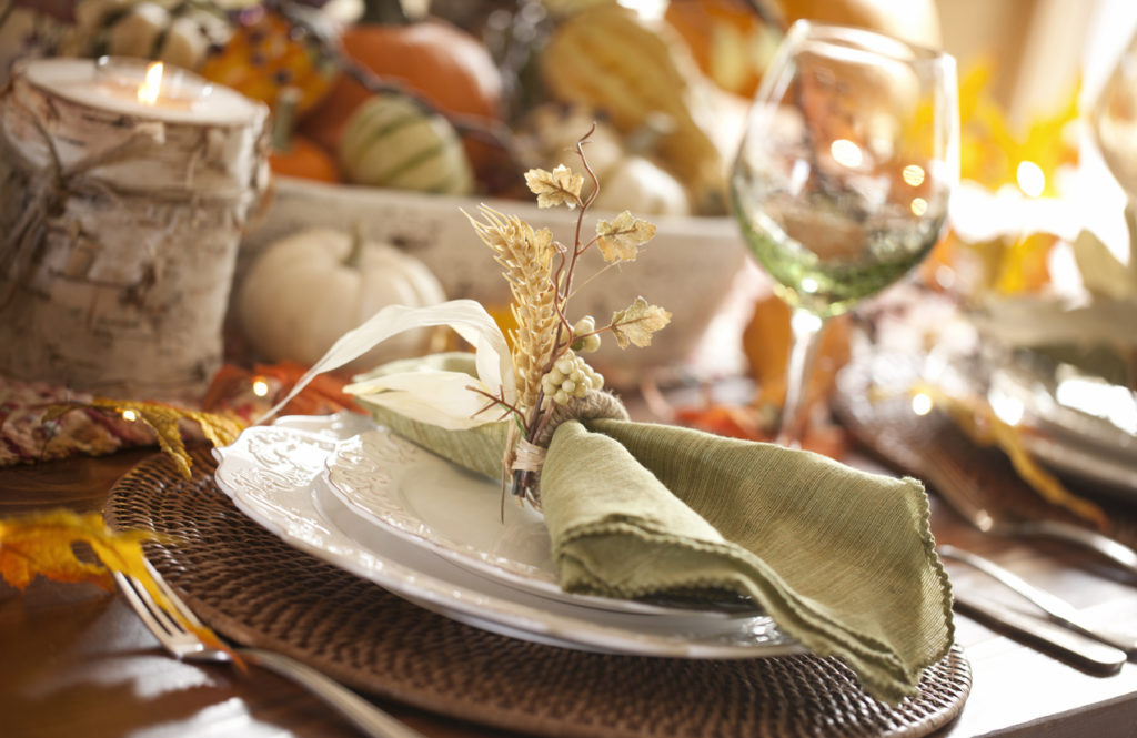 Thanksgiving dining table with beautiful traditional centerpiece filled with pumpkins and gourds.
