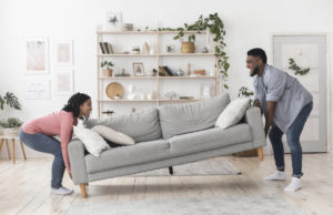 Couple moving sofa in living room, replacing furniture at home