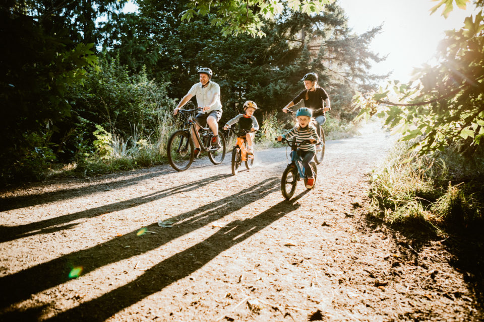 A father and mother ride mountain bikes together with their two small children.