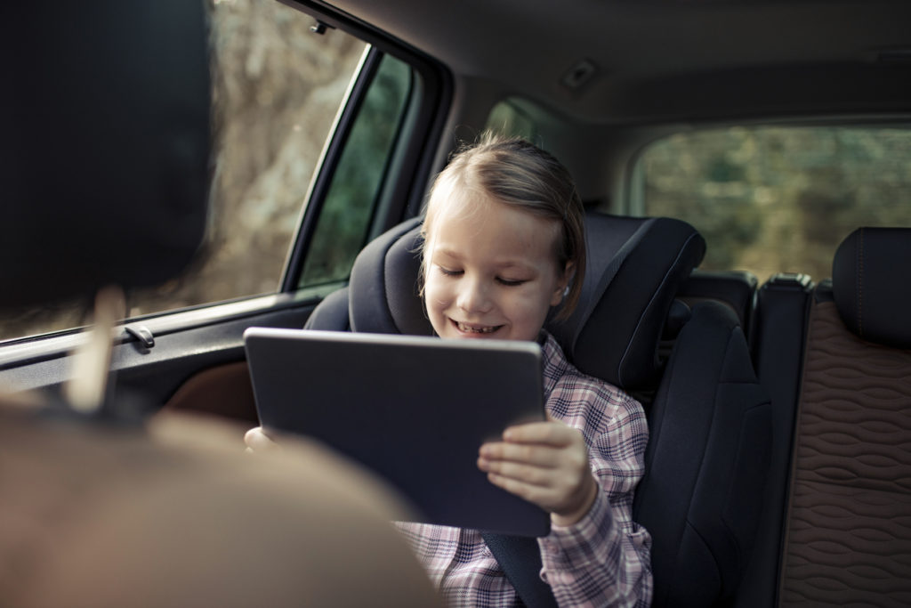Little girl playing games on her tablet during a road trip