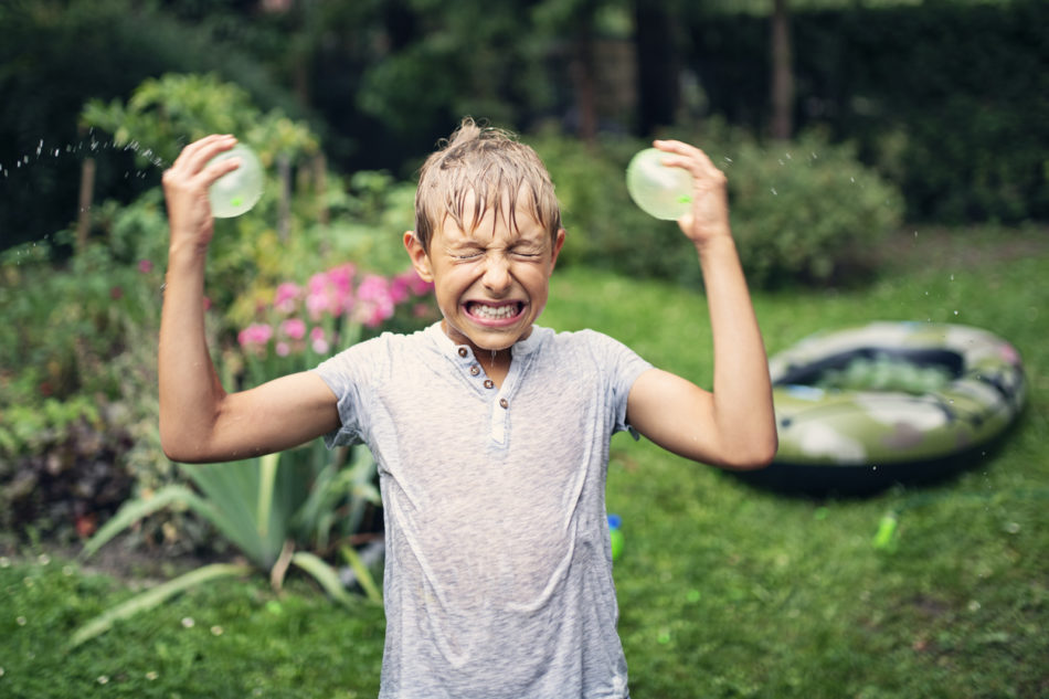 Funny little boy about to splash his head with water balloons.
