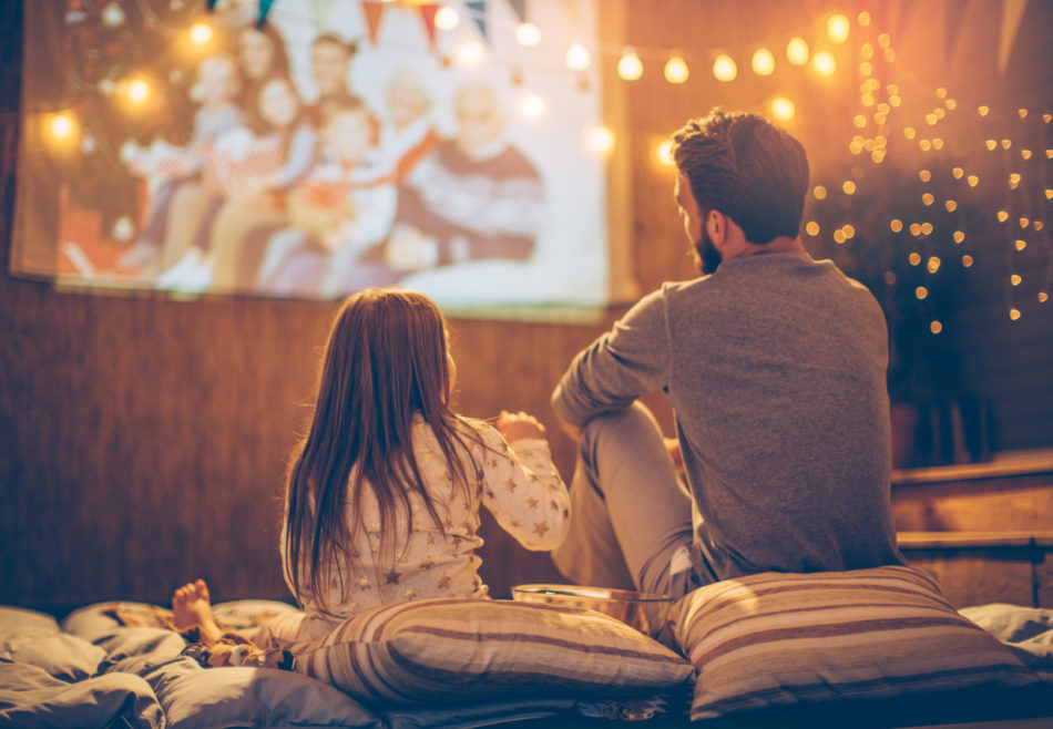 Father and daughter sitting at backyard and looking movie at home