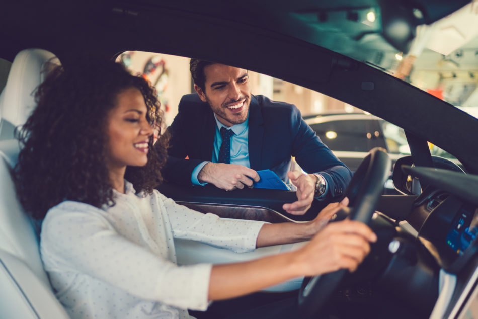 Smiling woman in the showroom enjoying luxury car