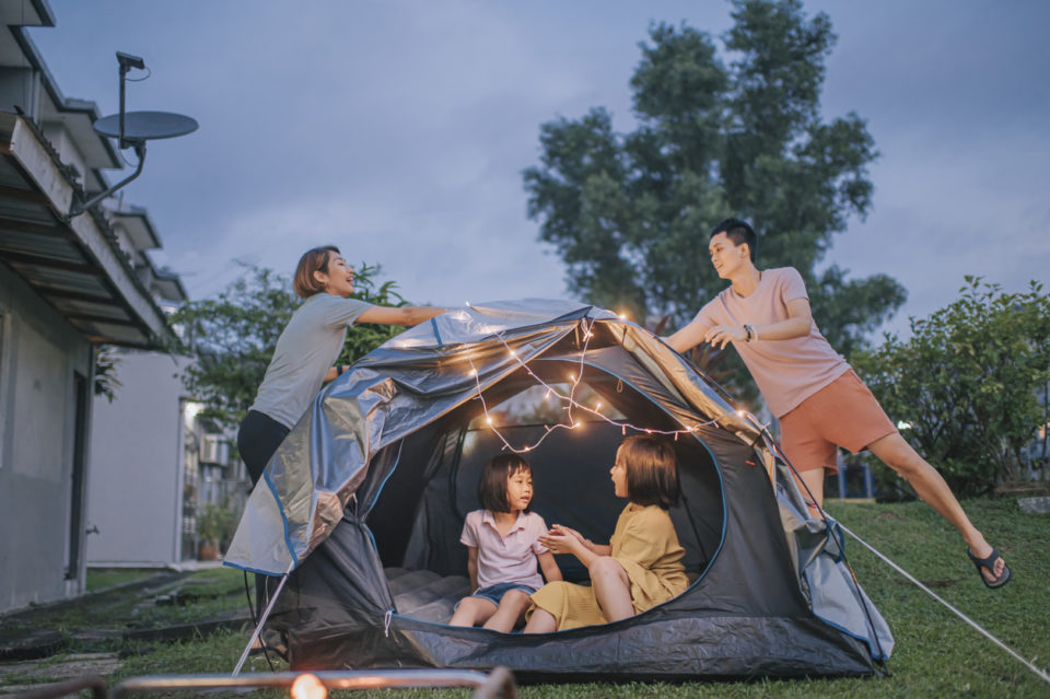 family putting on string light decorating camping at backyard of their house staycation weekend activities