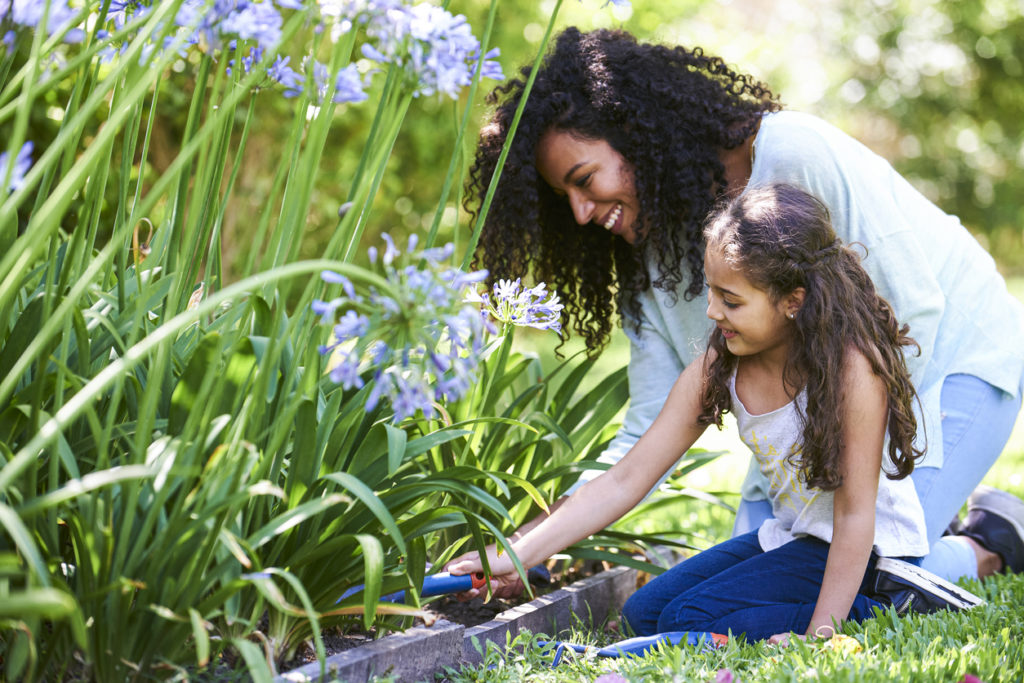 Mother and daughter planting together in garden