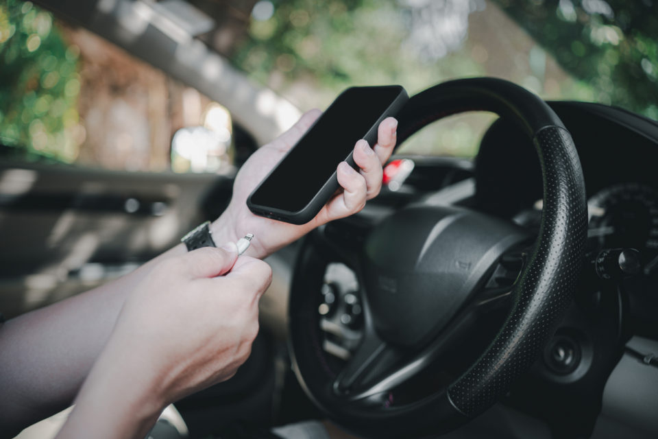 man plugging in phone to charge in vehicle