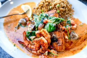 A Deliciously Prepared Mahi-mahi filet of fish Cajun Style topped with shrimp, crawfish and a white wine lemon butter sauce with a side of dirty rice