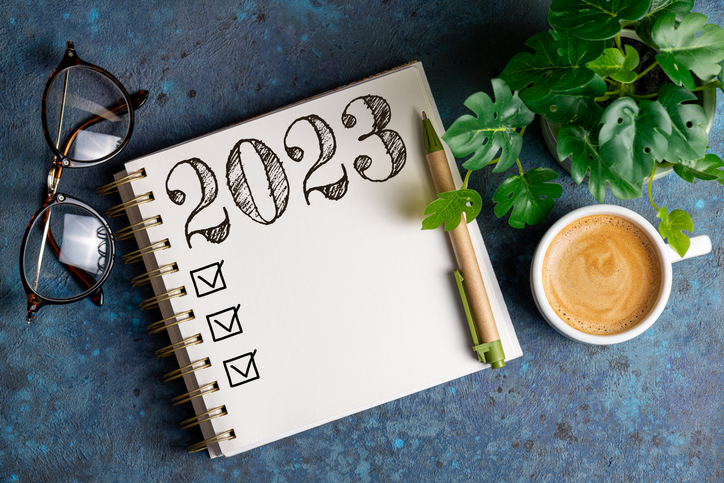 New year resolutions 2023 on desk. 2023 resolutions list with notebook, coffee cup on table.