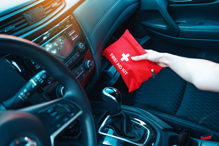 Female hand taking red first aid kit from the car glove box. A well-equipped car for road trips concept.