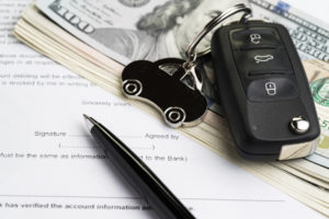 Buy or sell car, purchase or rent automobile service with key with car keychain on pile of US Dollar banknotes money on printed contract paper and pen to sign, finance installment or debt awareness.